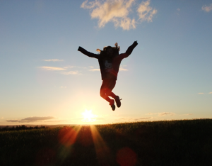 A girl jumping in her arms raised in silhouette photography