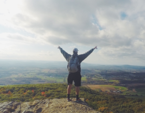 A man standing on high ground raising his arms