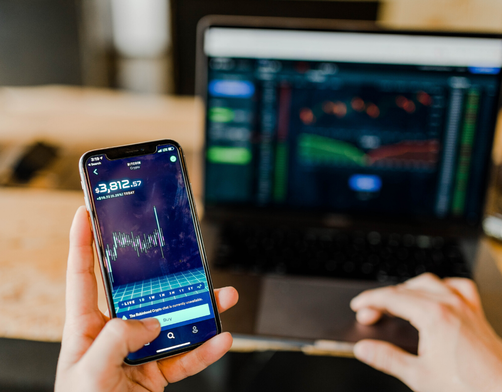 person using a phone and laptop to buy bitcoins