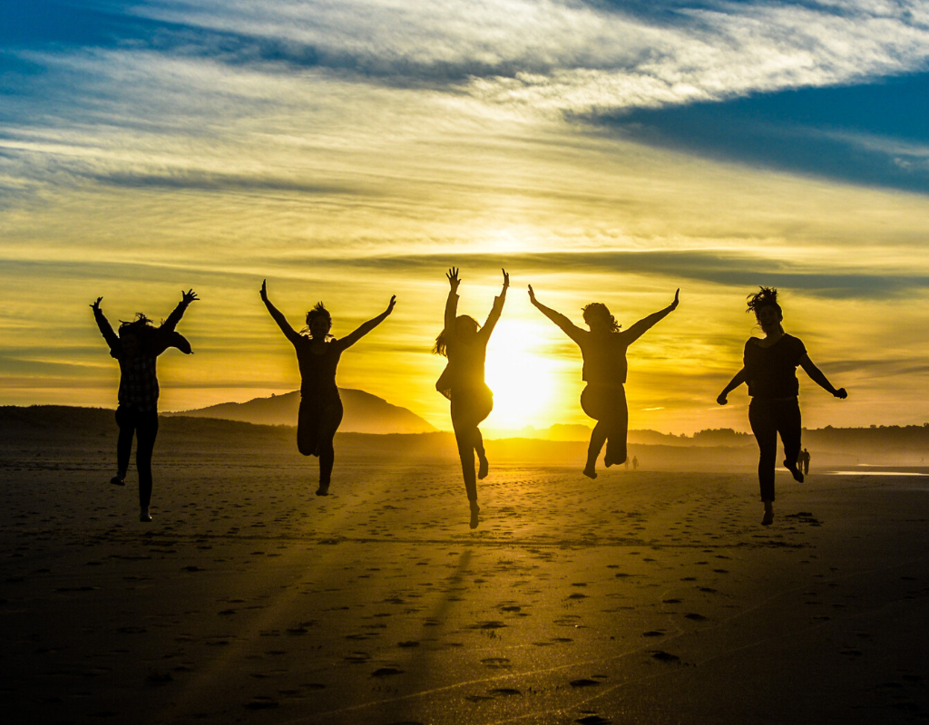 5 girls jumping and raising their arms in silhouette photography